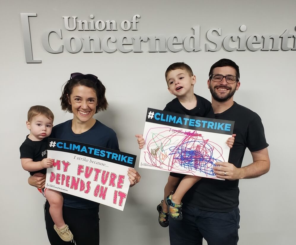 Gretchen Goldman and her husband both holding their young sons while holding Climate Strike posters